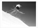 1950s man skier skiing down slope jumping into air by Anonymous