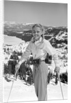 1940s 1950s young blond athletic woman looking at camera smiling standing with ski poles top of mountain by Anonymous