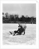 1920s 1930s two smiling boys looking at camera ice skating one boy fallen other picking him up by Anonymous