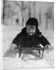 1930s young smiling boy on sled in snow looking at camera by Anonymous