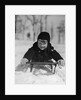 1930s young smiling boy on sled in snow looking at camera by Anonymous