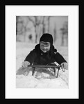1930s young smiling boy on sled in snow looking at camera by Anonymous