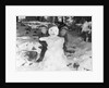 1950s 1960s smiling boy and girl building a snowman together in snowy woods by Anonymous