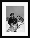 1920s 1930s smiling boy wearing aviator goggles leather flying helmet holding sled standing in snow field looking at camera by Anonymous