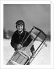 1920s 1930s smiling boy wearing aviator goggles leather flying helmet holding sled standing in snow field looking at camera by Anonymous