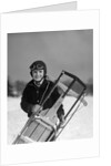 1920s 1930s smiling boy wearing aviator goggles leather flying helmet holding sled standing in snow field looking at camera by Anonymous