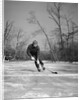 1940s man playing ice hockey on frozen lake controlling puck with stick by Anonymous
