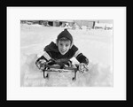1950s boy on sled in snow looking at camera by Anonymous