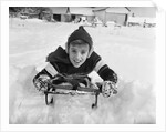 1950s boy on sled in snow looking at camera by Anonymous