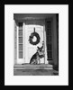 1930s german shepherd dog sitting front door stoop porch holding christmas package in his mouth by Anonymous