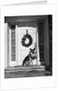 1930s german shepherd dog sitting front door stoop porch holding christmas package in his mouth by Anonymous