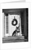 1930s german shepherd dog sitting front door stoop porch holding christmas package in his mouth by Corbis