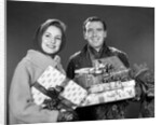 1960s smiling couple man and woman holding wrapped christmas presents and packages by Anonymous