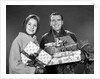 1960s smiling couple man and woman holding wrapped christmas presents and packages by Anonymous