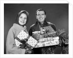 1960s smiling couple man and woman holding wrapped christmas presents and packages by Anonymous