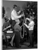 1960s family father mother two sons trimming christmas tree with string of popcorn by Anonymous