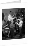 1960s family father mother two sons trimming christmas tree with string of popcorn by Anonymous