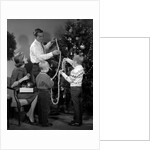 1960s family father mother two sons trimming christmas tree with string of popcorn by Anonymous
