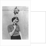 1930s 1940s cute young woman standing under mistletoe smiling hand near mouth looking at camera by Anonymous