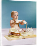 1960s baby surprised facial expression holding telephone hand set over yellow pages phone book directory by Anonymous