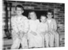 Siblings perch on a hearth in pajamas, ca. 1970. by Anonymous