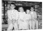 Siblings perch on a hearth in pajamas, ca. 1970. by Anonymous