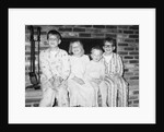 Siblings perch on a hearth in pajamas, ca. 1970. by Anonymous
