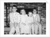 Siblings perch on a hearth in pajamas, ca. 1970. by Anonymous