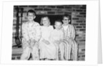 Siblings perch on a hearth in pajamas, ca. 1970. by Anonymous