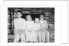 Siblings perch on a hearth in pajamas, ca. 1970. by Anonymous