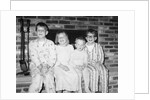 Siblings perch on a hearth in pajamas, ca. 1970. by Anonymous