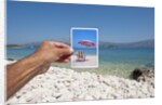 Hand holding photograph depicting deck chair and sunshade, Lumbarda, Korcula island, Croatia by Anonymous
