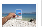 Hand holding photograph depicting deck chair and sunshade, Lumbarda, Korcula island, Croatia by Anonymous