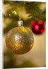 Close-up of a golden hanging Christmas bauble on blurred tree by Anonymous