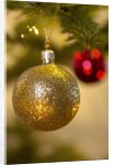 Close-up of a golden hanging Christmas bauble on blurred tree by Anonymous
