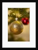 Close-up of a golden hanging Christmas bauble on blurred tree by Anonymous