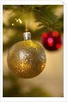 Close-up of a golden hanging Christmas bauble on blurred tree by Anonymous