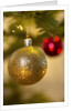Close-up of a golden hanging Christmas bauble on blurred tree by Anonymous