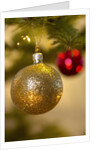 Close-up of a golden hanging Christmas bauble on blurred tree by Anonymous