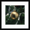 Close-up of a golden hanging Christmas bauble on blurred tree by Anonymous