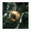 Close-up of a golden hanging Christmas bauble on blurred tree by Anonymous