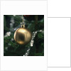 Close-up of a golden hanging Christmas bauble on blurred tree by Anonymous