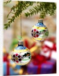 Close-up of decorated hanging baubles against blurred gifts in the background by Anonymous