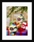 Close-up of decorated hanging baubles against blurred gifts in the background by Anonymous