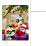 Close-up of decorated hanging baubles against blurred gifts in the background by Anonymous