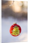 Close-up of golden Christmas tree on red bauble against blurred background by Anonymous
