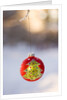 Close-up of golden Christmas tree on red bauble against blurred background by Anonymous