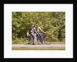 1970s Family On Tandem Bicycle Mother Father Son & Baby Daughter In Backpack Wearing Bellbottom Blue Jeans Looking At Camera by Anonymous