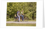 1970s Family On Tandem Bicycle Mother Father Son & Baby Daughter In Backpack Wearing Bellbottom Blue Jeans Looking At Camera by Anonymous