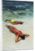1990s Couple Sunbathing In Shallow Water At The Ocean's Edge by Anonymous